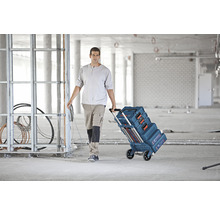 Handwerker zieht einen Werkzeugkofferwagen von Bosch durch eine Baustelle.