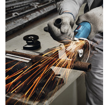 Eine Person schneidet mit einem Winkelschleifer ein Metallrohr. Funken fliegen.