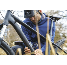 Mann befestigt mit Panzertape einen Flaschenhalter an einem Fahrrad.