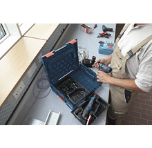 Handwerker mit Werkzeugkoffer und Akkuschrauber auf einer Werkbank