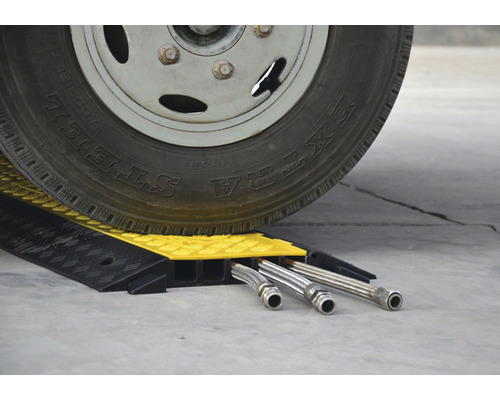 Ein Fahrzeugreifen fährt über einen Kabelschutz mit Kabelkanälen.