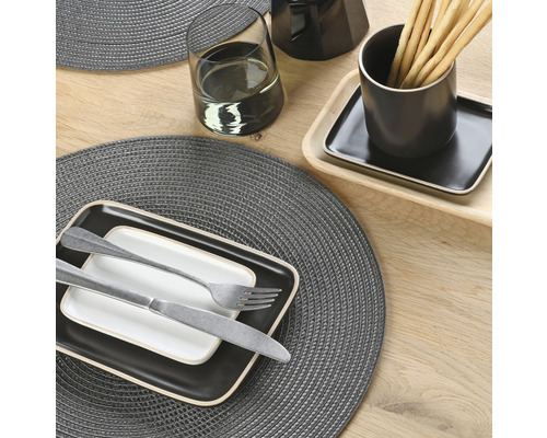 Tischdekoration mit Platzsets, Geschirr und Besteck auf Holztisch