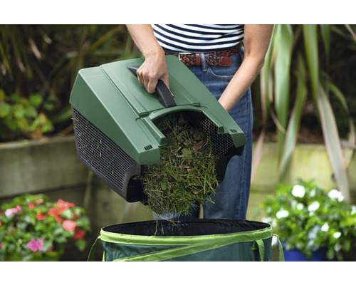 Person leert Gras und Laub mit einer Kehrmaschine in einen Gartensack