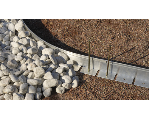 Gartenlandschaft mit Rasenkante aus Metall, befestigt mit Erdnägeln, und dekorativen Steinen