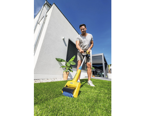 Mann benutzt eine Fugenbürste im Garten