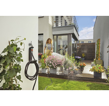 Frau gießt Blumen mit einem Gartenschlauch im Garten