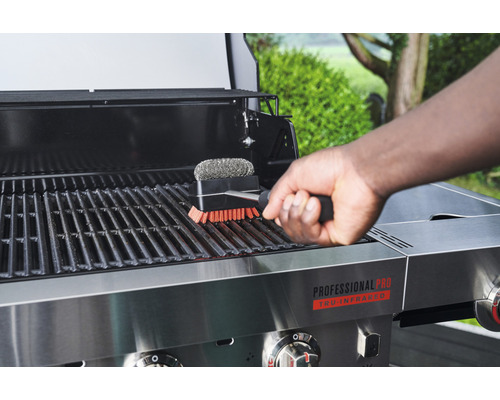 Person reinigt Grillrost mit Grillbürste
