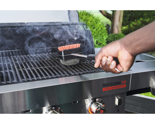 Eine Person reinigt einen Grill mit einer Grillbürste.