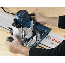 Person benutzt Oberfräse auf einer Führungsschiene von Bosch