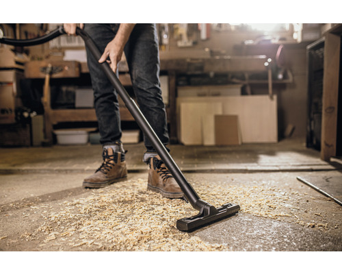 Eine Person saugt Holzspäne mit einem Staubsauger auf.