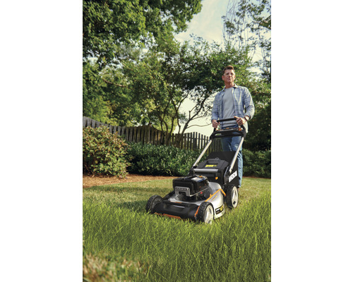 Mann schiebt einen Rasenmäher im Garten.