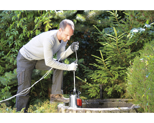 Mann installiert eine Tauchpumpe im Gartenbrunnen.