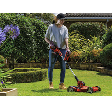 Frau benutzt Akku-Rasenkantenschneider im Garten.