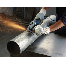 Eine Person benutzt eine Schleifmaschine an einem Rohr, Funken fliegen.