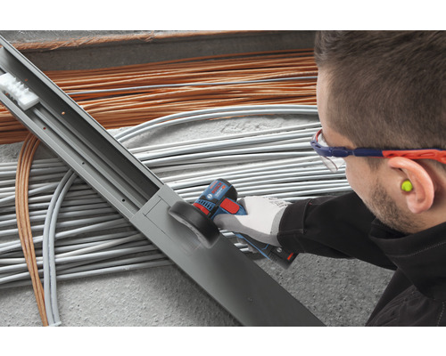 Handwerker mit Elektrowerkzeug beim Bearbeiten einer Kabelrinne.