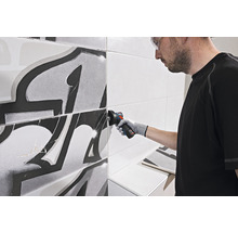 Fliesenleger schneidet Fliese mit Winkelschleifer