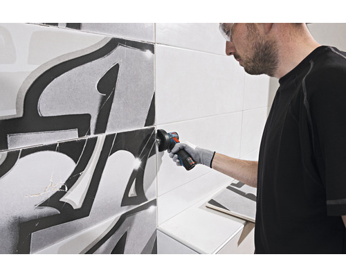 Fliesenleger schneidet Fliese mit Winkelschleifer