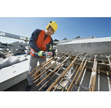 Ein Mann mit Schutzhelm, Schutzbrille und Gehörschutz schneidet mit einem Winkelschleifer Armierungseisen.