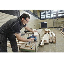 Ein Mann benutzt eine Stichsäge, um ein Stück Holz zu schneiden.