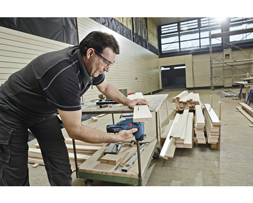 Ein Mann benutzt eine Stichsäge, um ein Stück Holz zu schneiden.