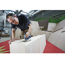 Mann sägt Holz mit einer Stichsäge. Die Stichsäge ist von Bosch.