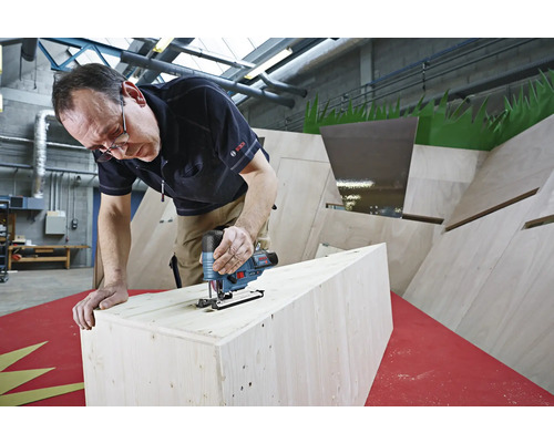 Mann sägt Holz mit einer Stichsäge. Die Stichsäge ist von Bosch.