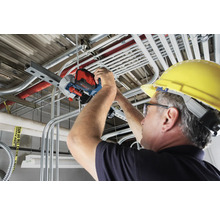 Ein Mann mit Schutzhelm verwendet eine Rohrtrennsäge für Metallrohre.