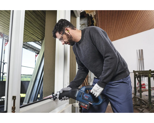 Mann arbeitet mit einer Akku-Säbelsäge an einem Fensterrahmen.