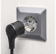 Steckdose mit eingestecktem Stecker an der Wand