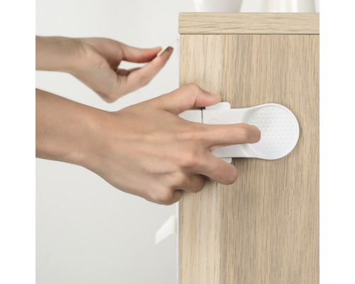 Eine Person befestigt eine Schranksicherung an einem Holzschrank.
