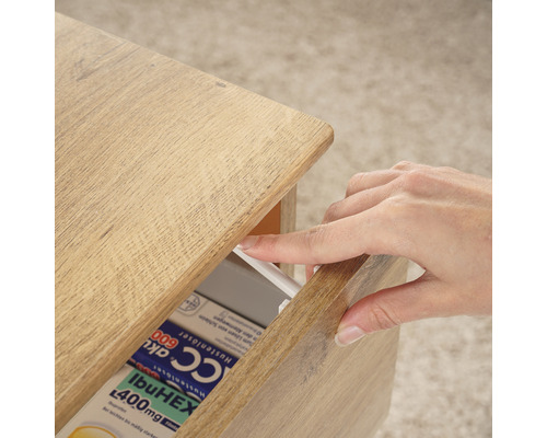 Holzkommode mit einer Hand, die eine Schublade mit Medikamenten öffnet.
