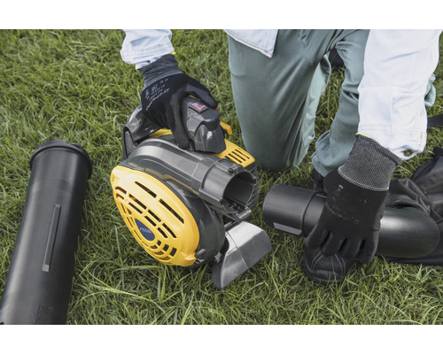 Eine Person montiert einen gelbgrauen Laubsauger auf einer Rasenfläche.