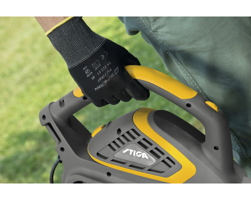 Eine Person hält eine Stiga Heckenschere mit einer Hand mit Handschuh am Griff.