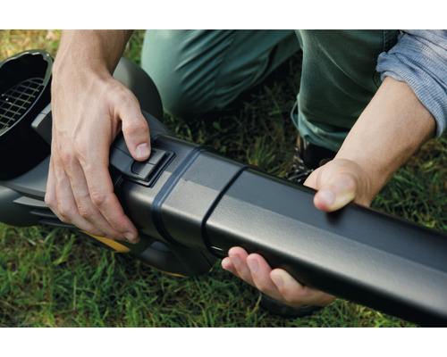 Eine Person montiert ein Gebläse auf Rasen.