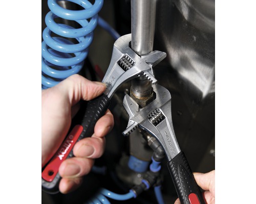 Zwei verstellbare Schraubenschlüssel werden zum Festziehen einer Rohrverbindung verwendet.