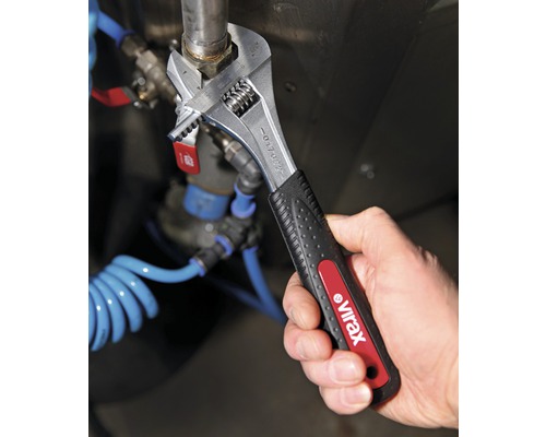 Eine Person benutzt einen verstellbaren Schraubenschlüssel von Virax an einer Rohrmutter.