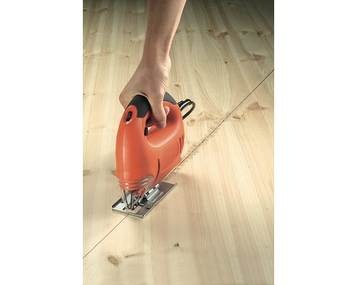 Person schneidet mit einer Stichsäge ein Holzbrett entlang einer Linie.