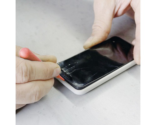 Person repariert ein Smartphone mit einem Schraubendreher.