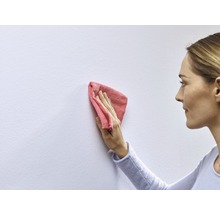 Eine Frau reinigt eine Wand mit einem Tuch.