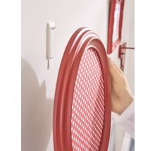 Ovaler Bilderrahmen wird mit einem Klebestreifen an einer Wand befestigt