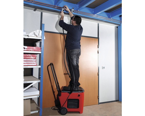 Mann steht auf einem Luftentfeuchter und montiert eine Leitung an der Decke