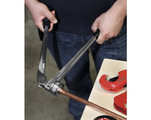 Eine Person verwendet eine Presszange zum Verpressen eines Kupferrohrs.