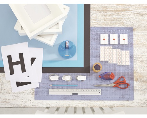 Bastelmaterialien mit Bilderrahmen, Buchstaben, Klebestreifen, Schere, Bleistift und Schneidematte