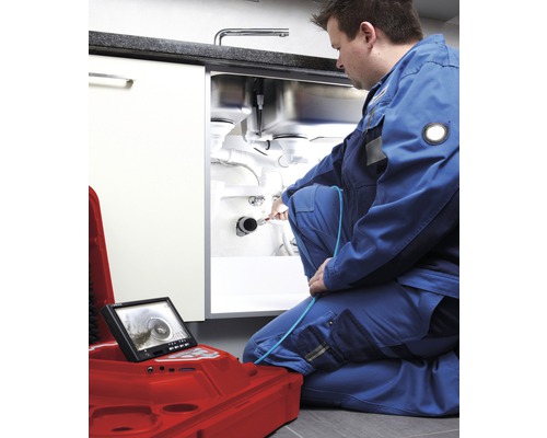 Ein Mann benutzt eine Rohrkamera zur Inspektion eines Abflusses unter einer Spüle.