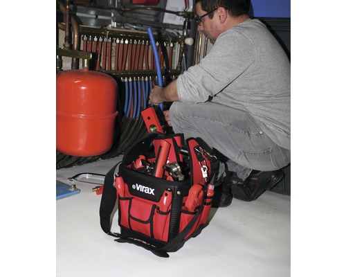 Ein Installateur arbeitet an einem Heizsystem mit einem Werkzeugkoffer der Marke Virax.