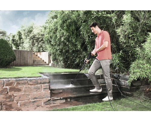 Mann reinigt Außentreppe mit Hochdruckreiniger im Garten.