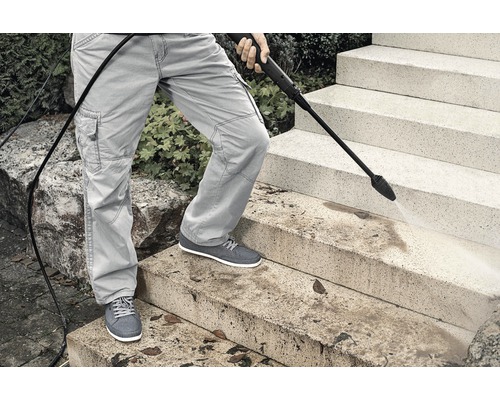 Person reinigt Treppe mit Hochdruckreiniger