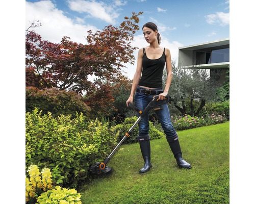Frau benutzt einen Rasentrimmer im Garten.