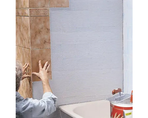 Fliesenleger bei der Arbeit im Badezimmer mit Fliesenkleber, Fliesen und Werkzeugen