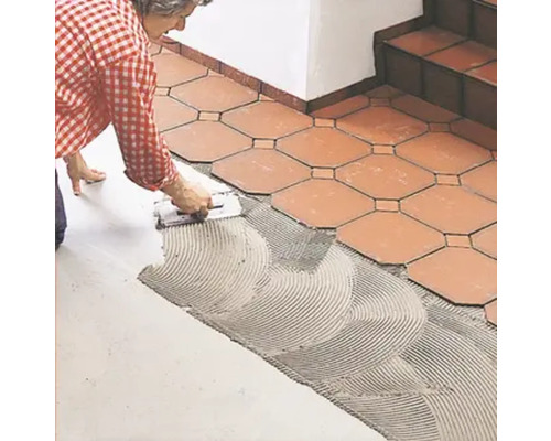 Fliesenleger verlegt Bodenfliesen mit Fliesenkleber